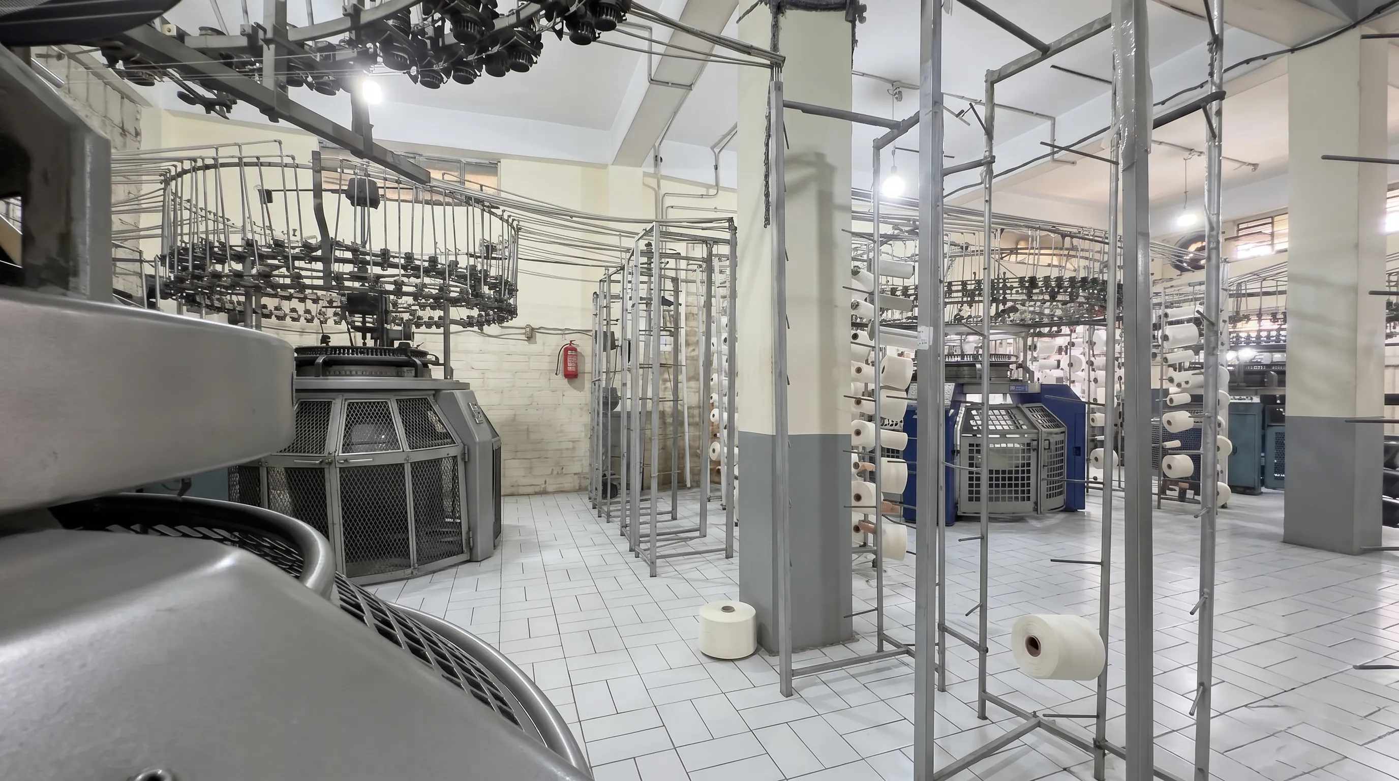 Six DSK circular knitting machines producing knitted grey fabric at Apex Corporation knitwear manufacturer facility in North Karachi Industrial Area Pakistan